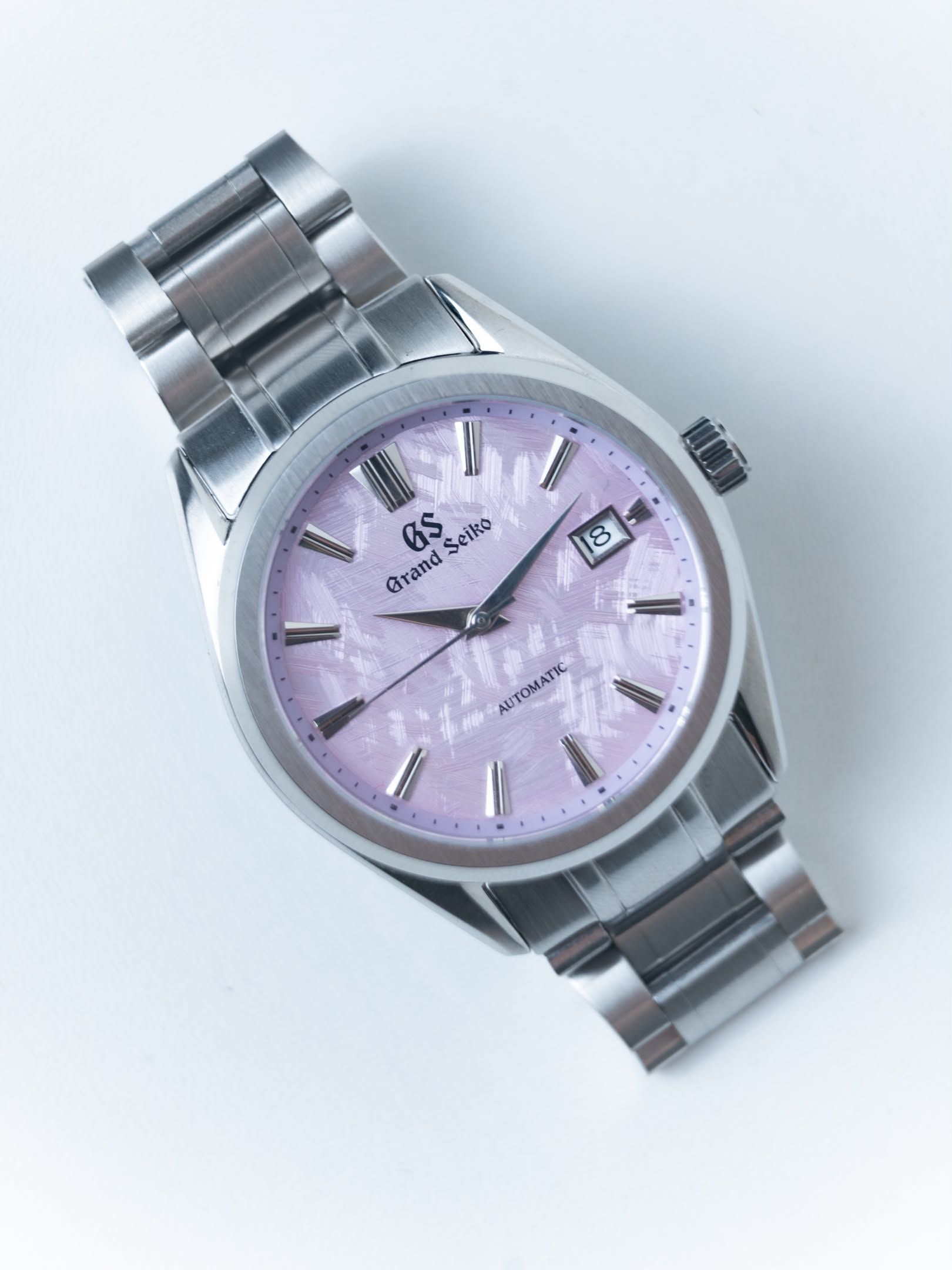 Cherry lying on its bracelet, the brushed lilac dial and polished batons in sharp focus.
