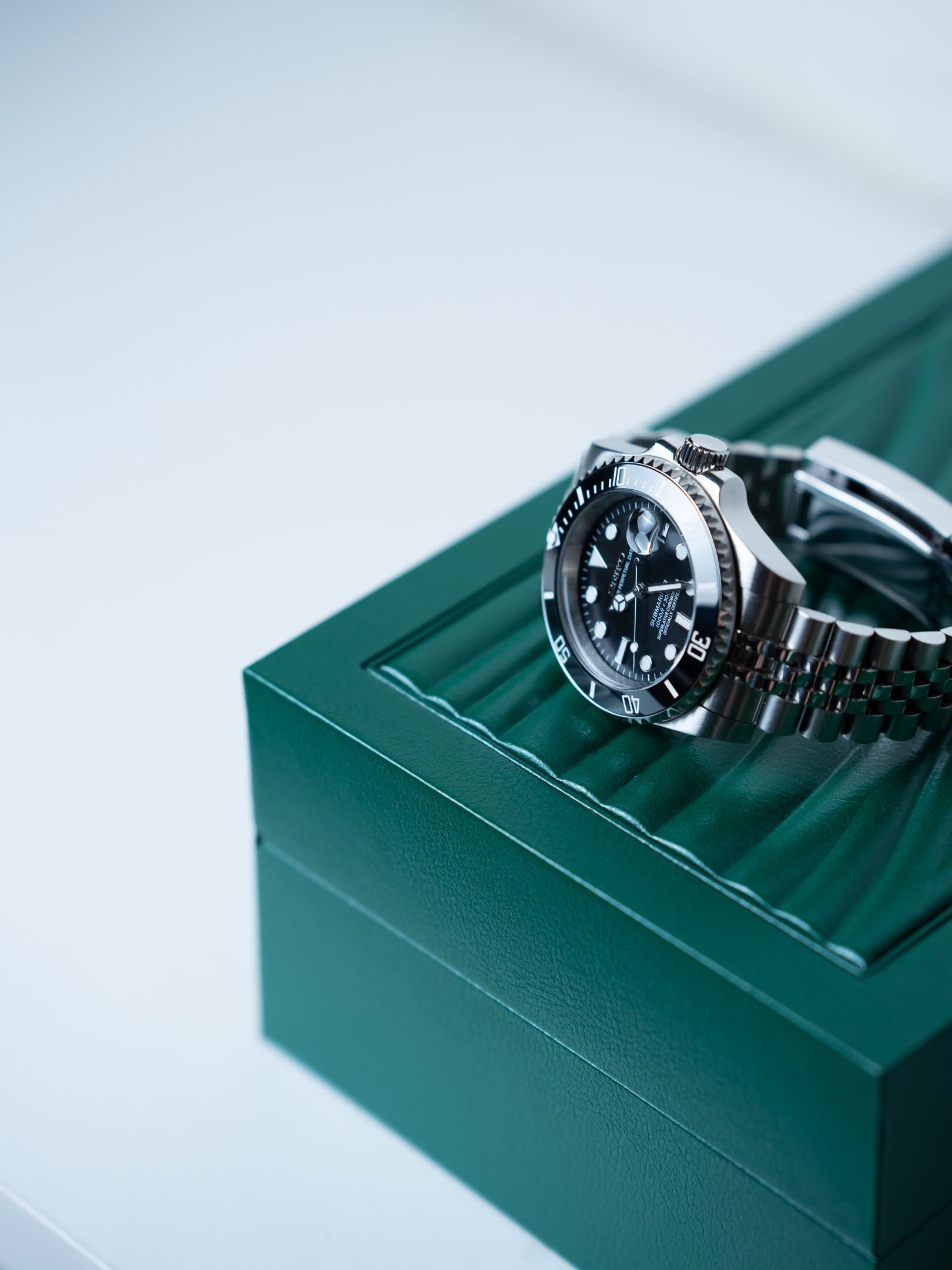 Ebony draped over the corner of a green watch box.